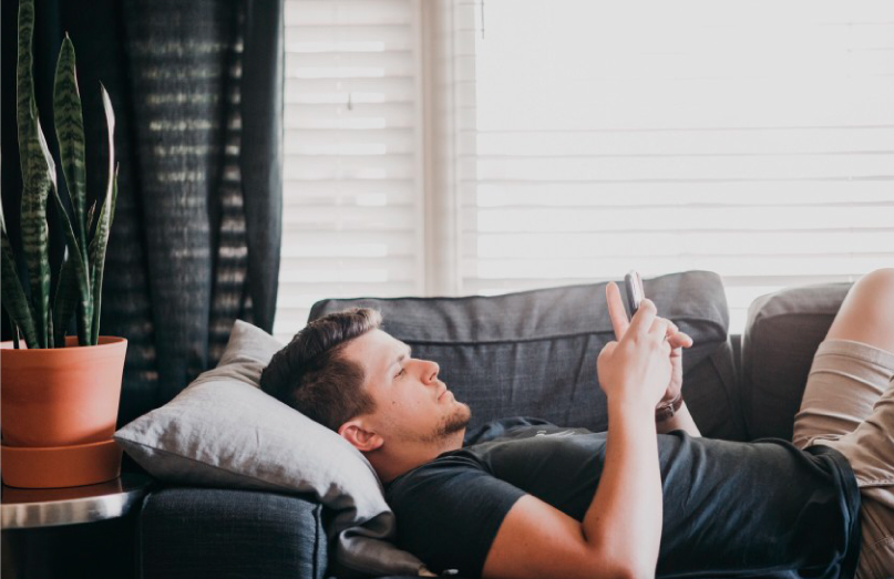 man on couch using smartphone minddemand